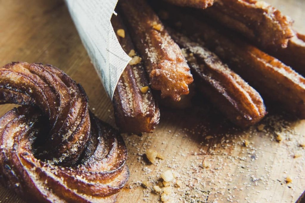 Close-up of churros on a chopping board sprinkled with nuts 