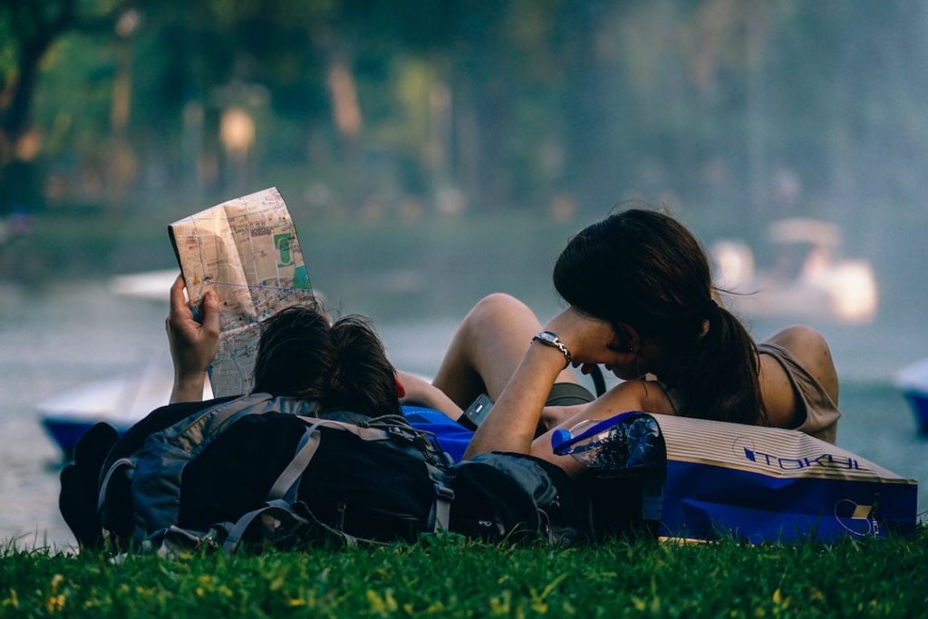 Two people looking at a map on grass outdoors.