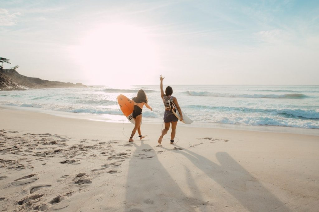 Two women with surfboards walking into the water in Prainha, Brazil