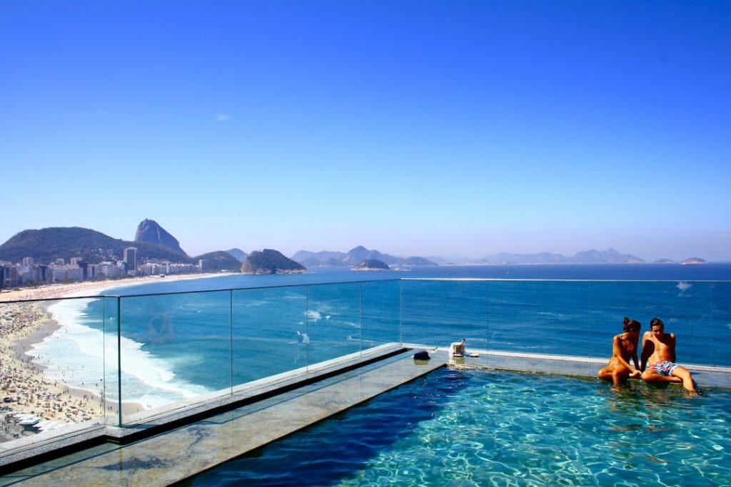 A couple sitting on the edge of an infinity pool above Rio de Janeiro, Brazil