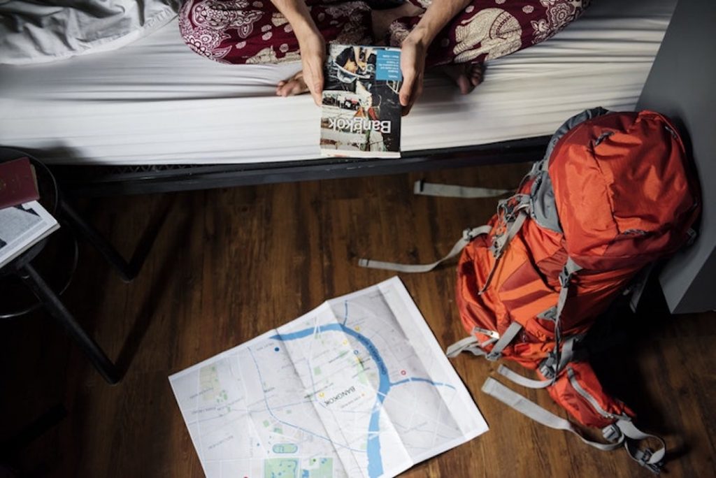 A traveller prepares for their trip with a map and travel guide