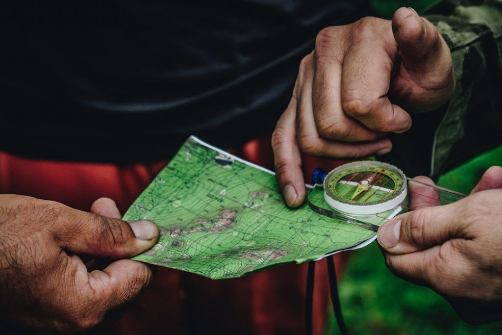 a close-up of two people holding a map and compass