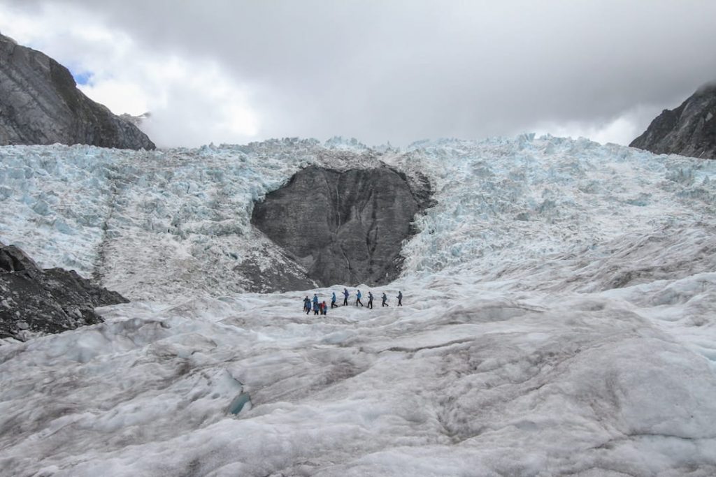  un groupe de personnes en manteau d'hiver randonnée le long du glacier Franz Josef en Nouvelle-Zélande 