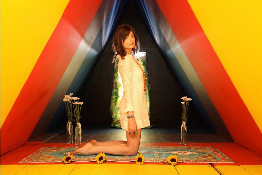 a woman in a white dress kneels on a yoga mat sitting on top of four sunflowers