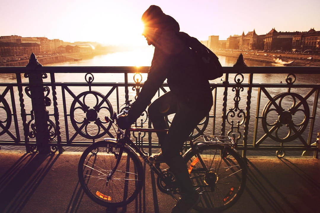 A man cycling at sunrise or sunset along the Danube River in Budapest