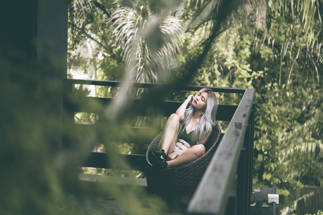 A girl sits in a corner of a balcony in the jungle