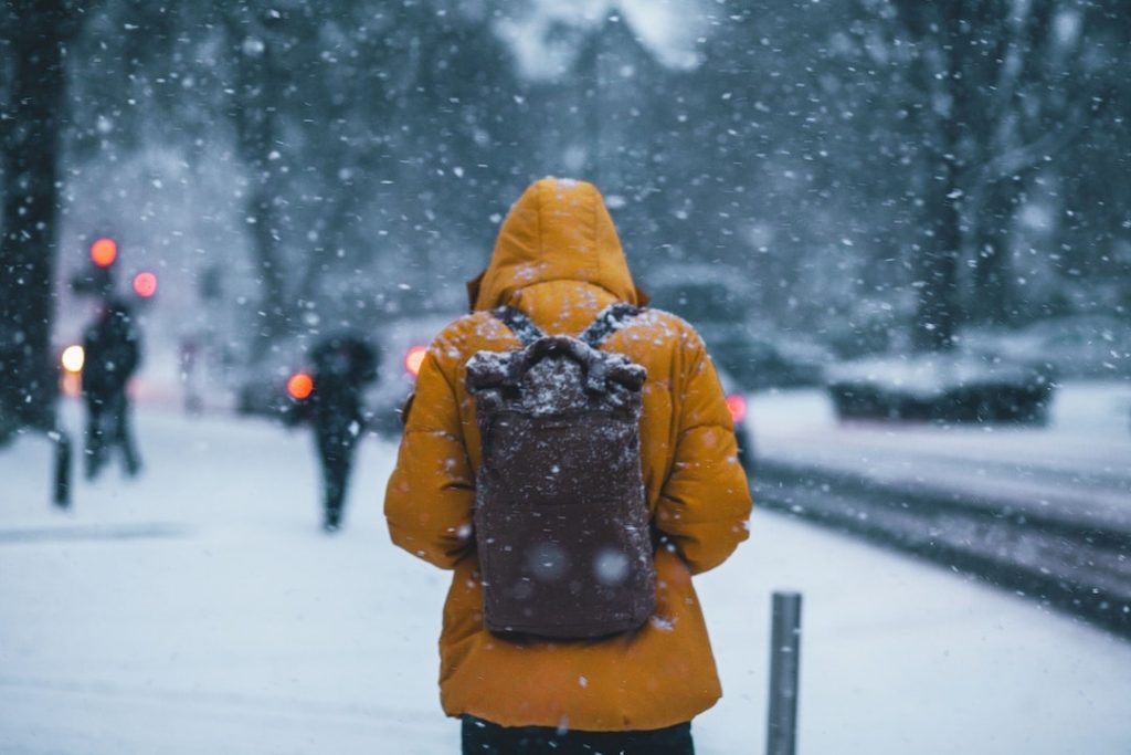 A person in a yellow coat walking in the snow