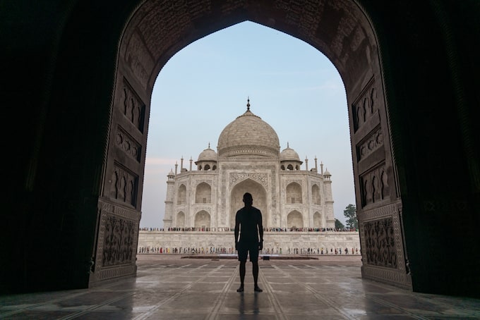 A man standing under an arch near the Taj Mahal