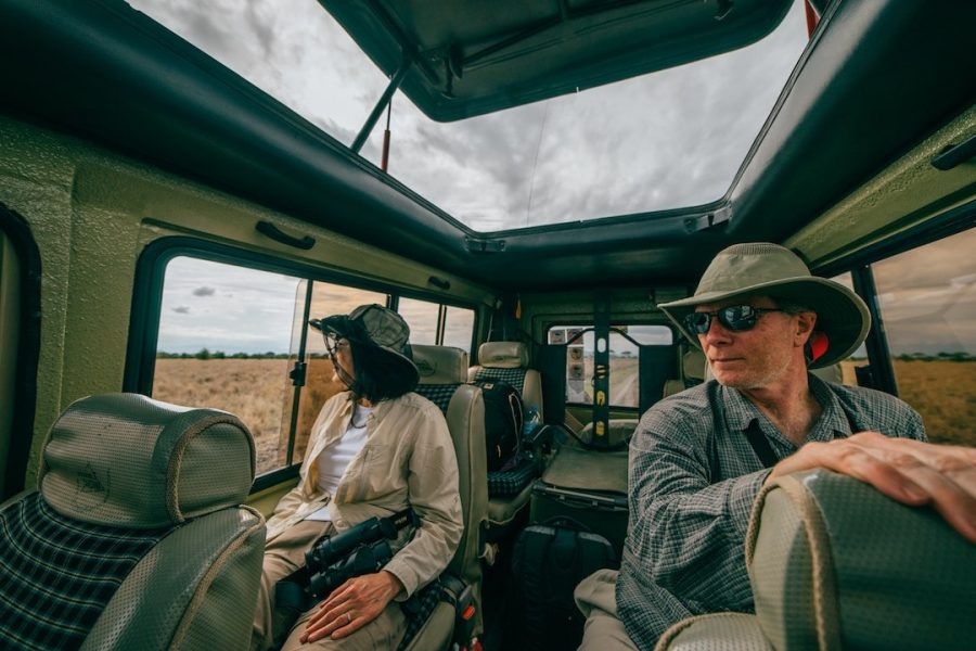 Two people in a safari truck wearing safari gear