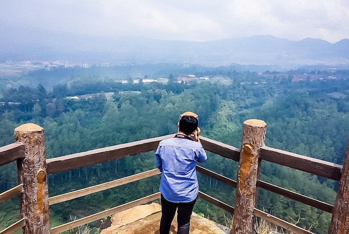 A man stands and takes a photo off a look-out point in Indonesia