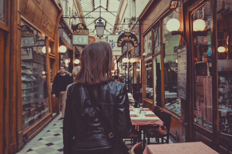 woman walking in hallway lined with cafes