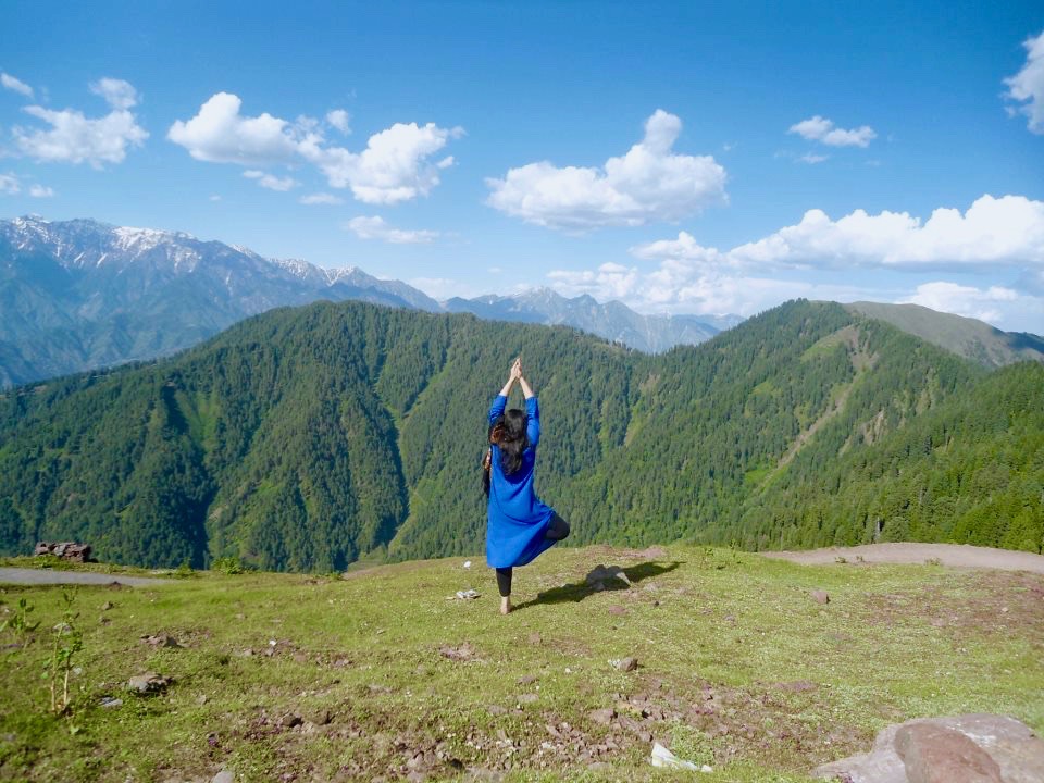 a woman doing a tree pose on a mountain top