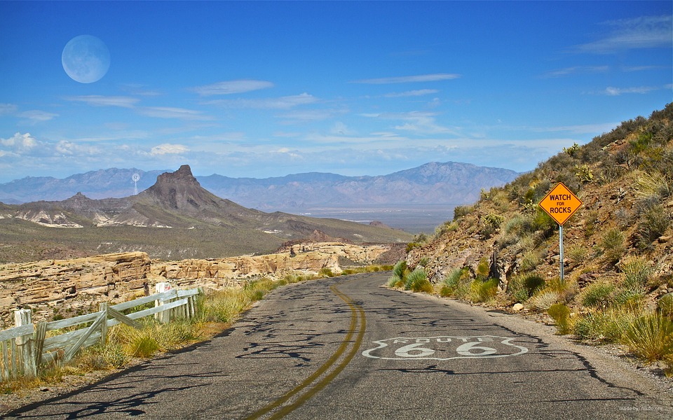 a route 66 sign market on a road through a patchy green highway