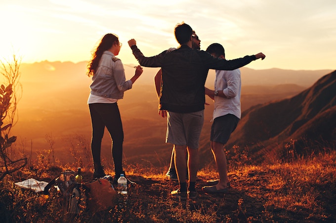 A group of people dancing outdoors at sunset