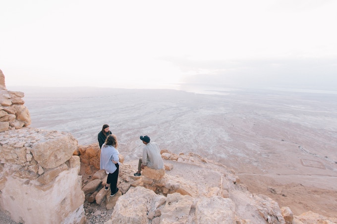 Three people on a cliff in Masada National Park, Israel