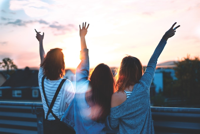 Three women with their backs to the camera with their arms in the air