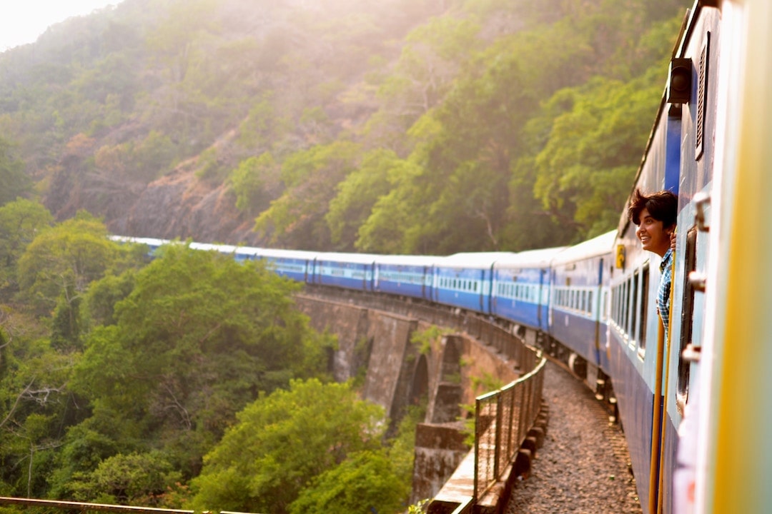 A woman leaning out the window of a train in Goa, India