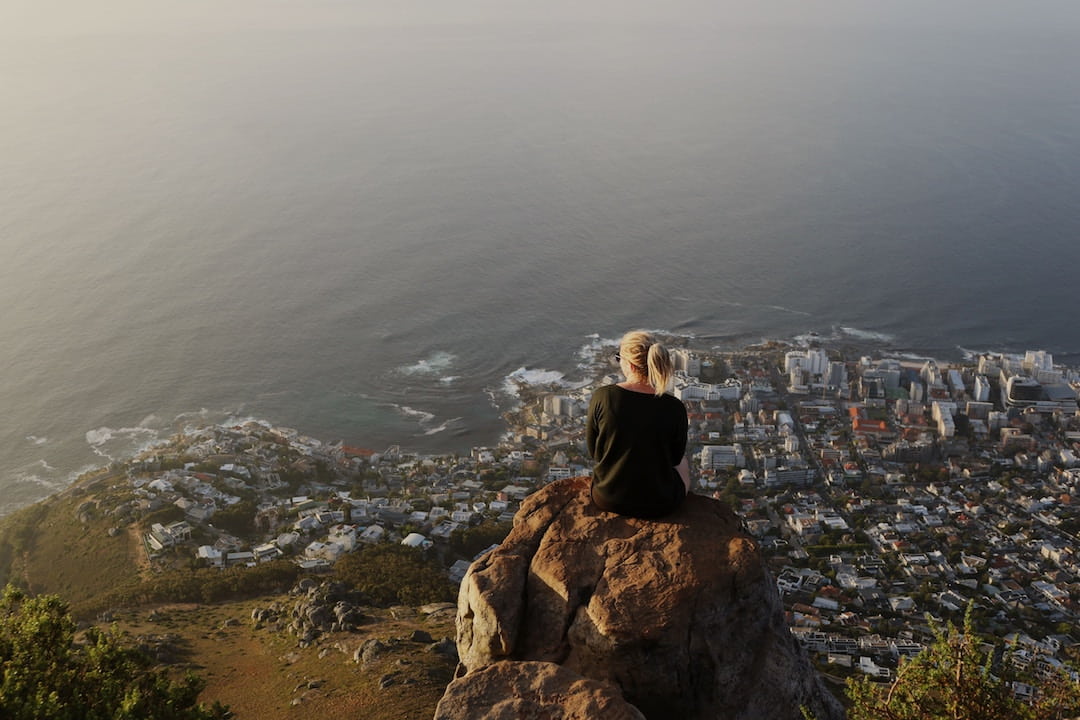 A woman sitting on Lion's Head looking over South Africa