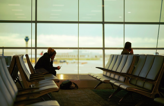 A woman wearing headphones sitting at an airport gate