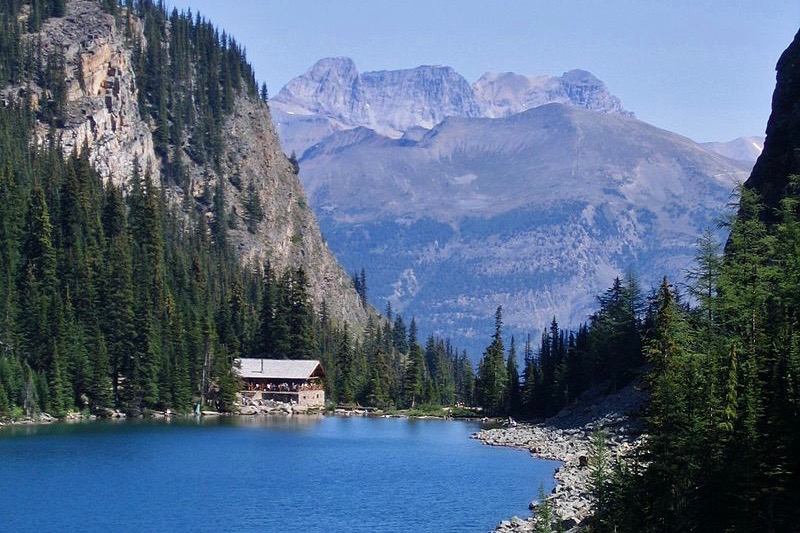 a small hut in a valley by a blue lake