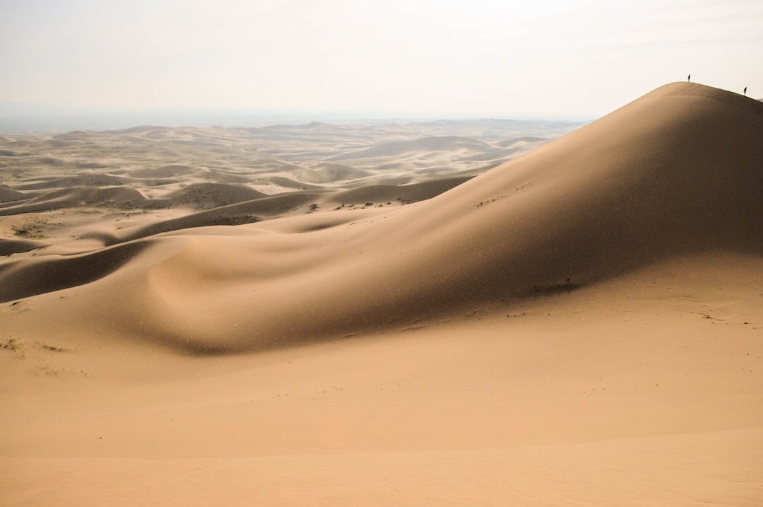 Two people standing on top of Khongoryn Els in the Gobi Desert, Mongolia