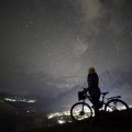 silhouette of a girl with a cycle against a night sky with stars