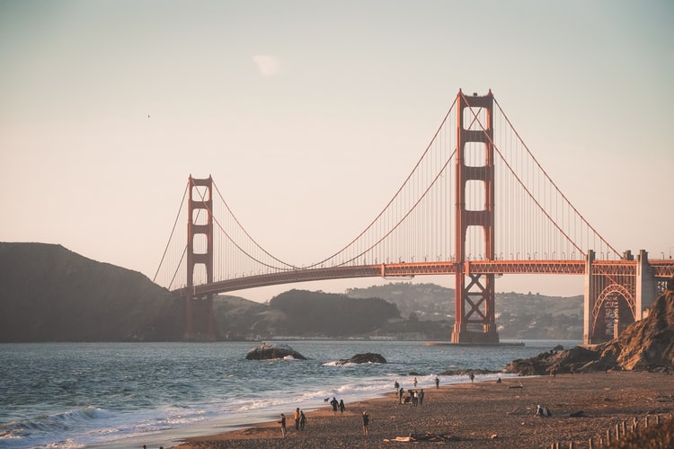 people walking near red bridge on body of water during daytime 