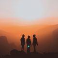 silhouette of three women standing in an orange sunset