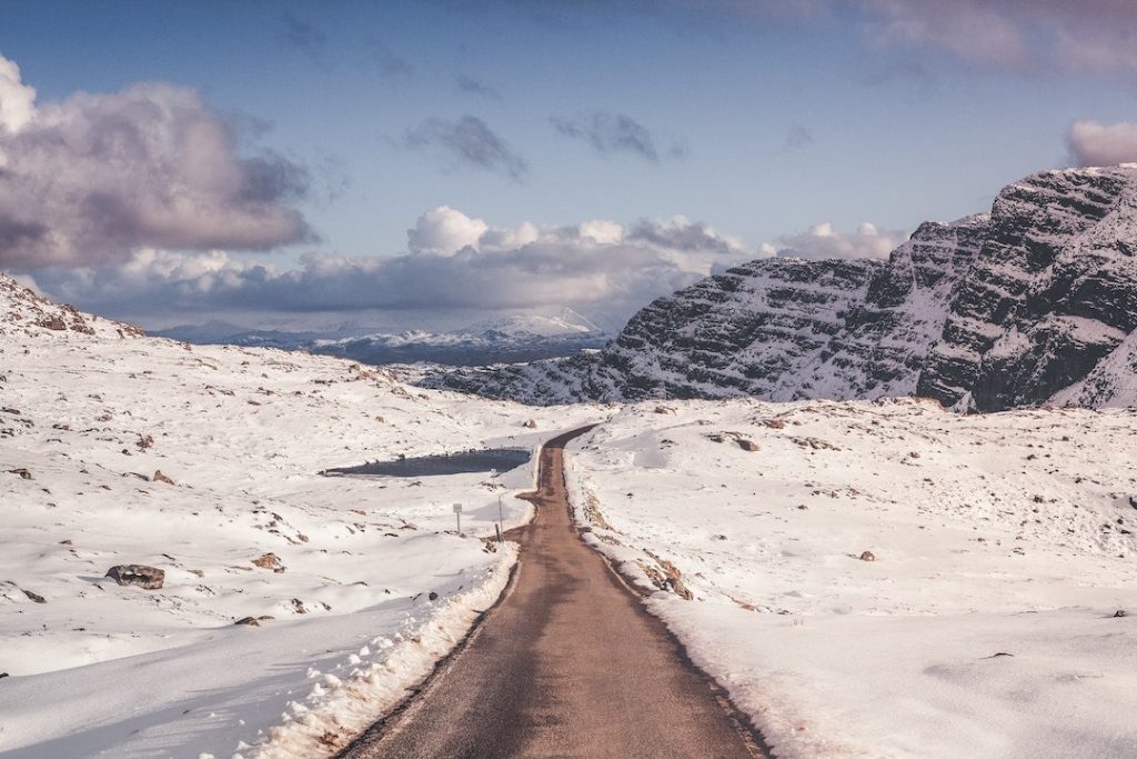 A road among snow-covered valleys in the Scottish Highlands