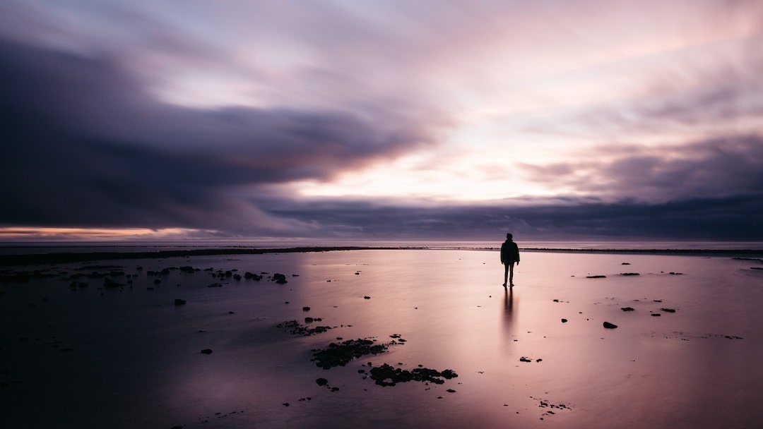 Person standing alone on a beach at sunset