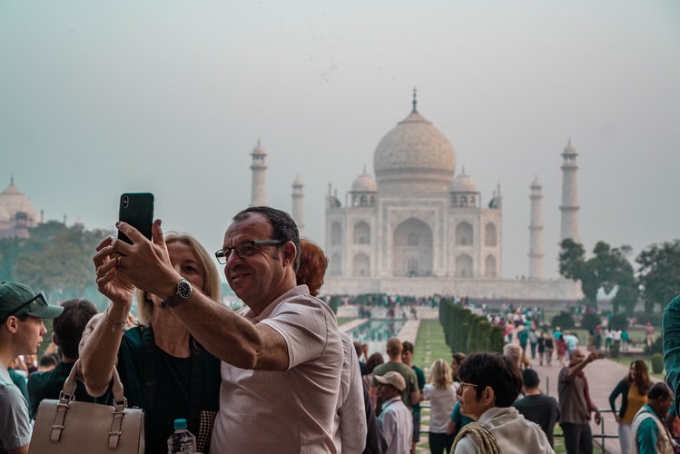 man and woman taking selfie in front of taj mahal