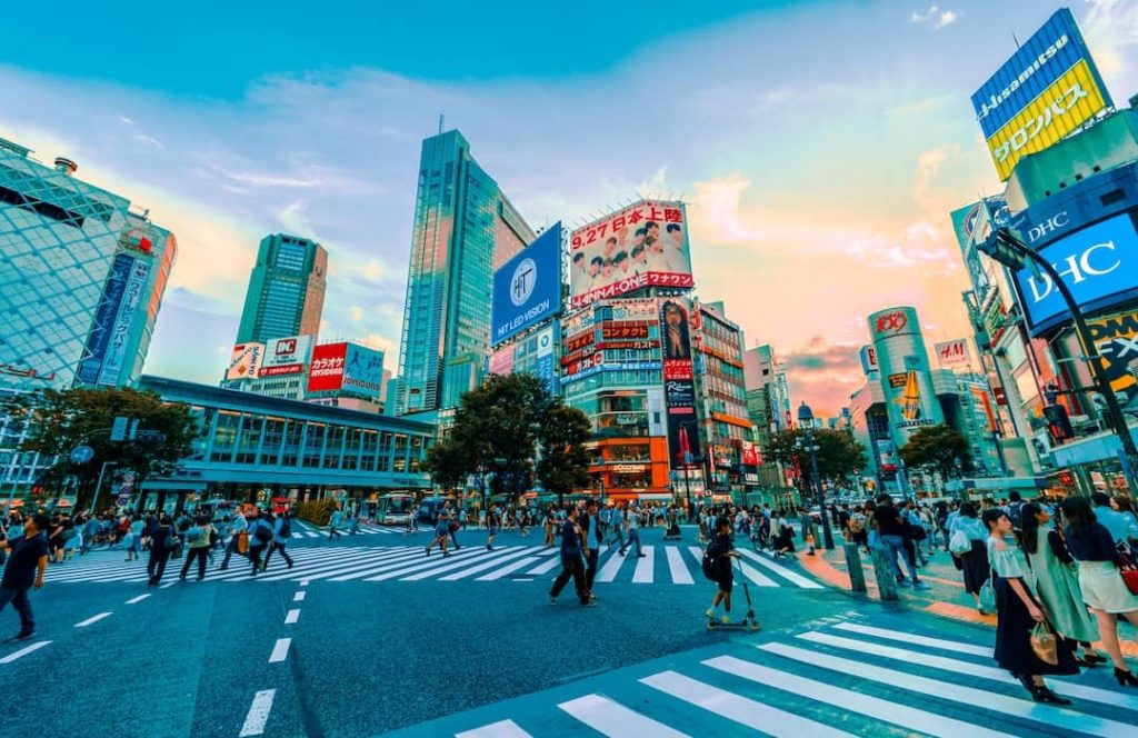 People walking across the street alongside skyscrapers in Tokyo, Japan