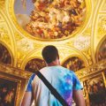 Man looking up at the ceiling in a historic building adorned with frescoes