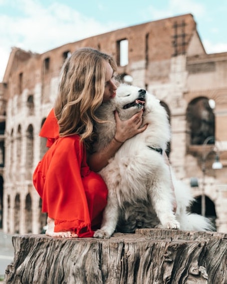 woman petting dog in front of an old building 