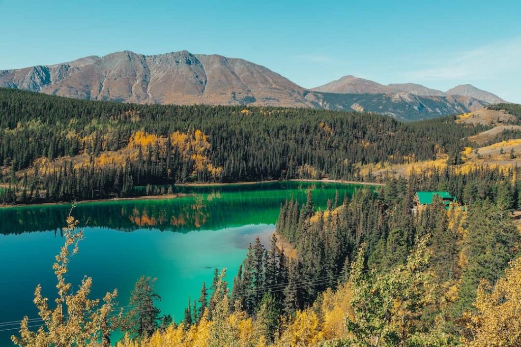 Mountains and a teal lake surrounded by forest in Yukon, Canada