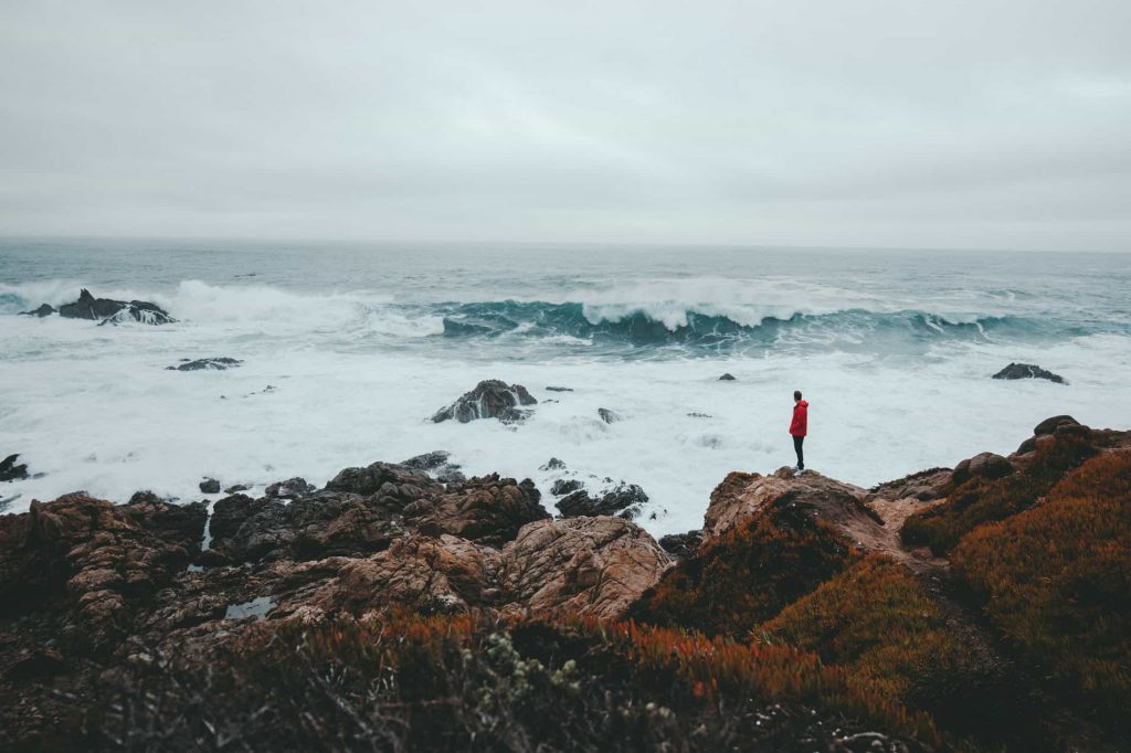 Person standing on rocks overlooking the ocean