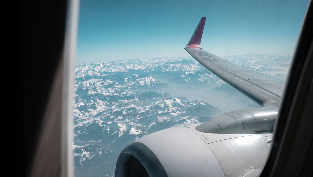 Airplane window view wing over mountain range