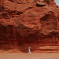 astronaut walking through a red desert landscape