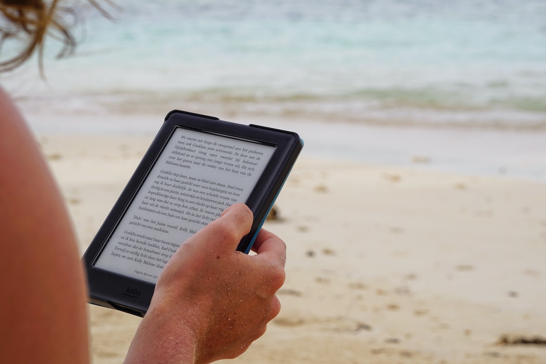 Person holding a kindle on the beach