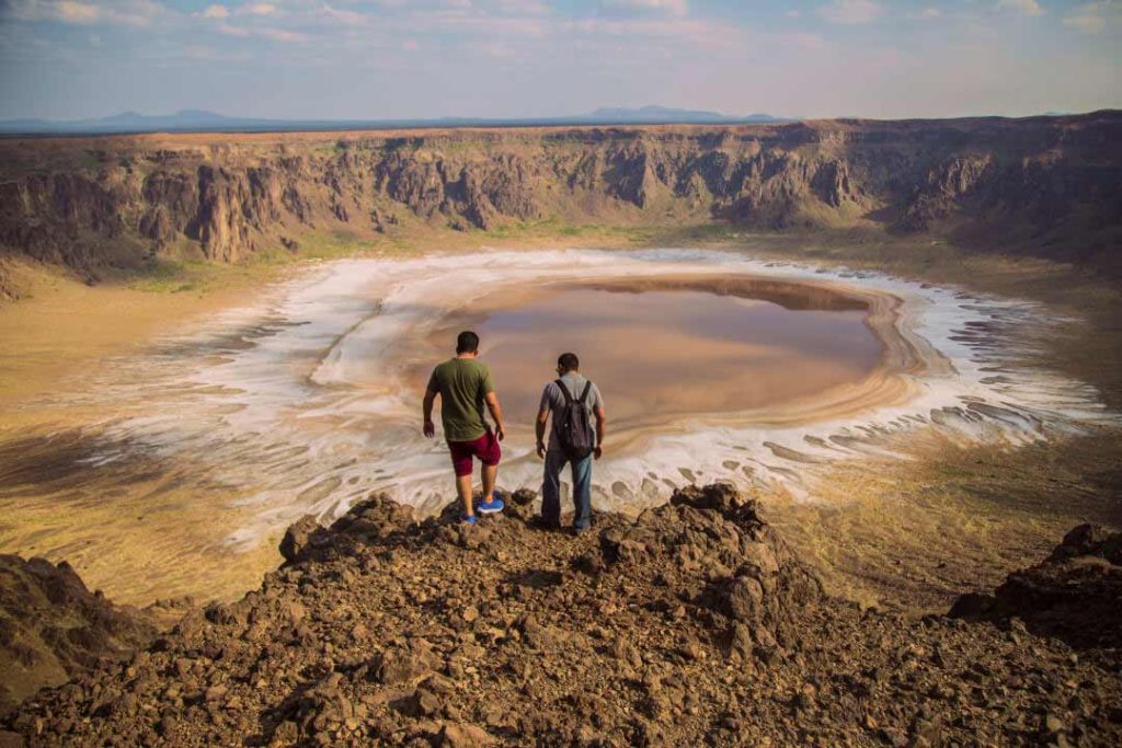 The images shows two men looking down at Al Wahba crater, one of Saudi Arabia’s most impressive natural wonders.